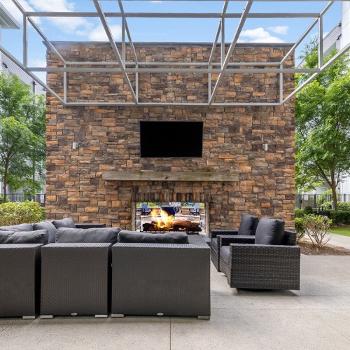 a patio with a tv, fire pit and chairs