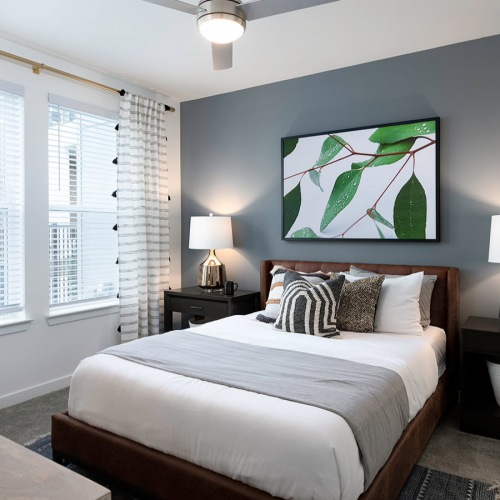 Bedroom large windows brighten carpeted bedroom with ceiling fan and light fixture